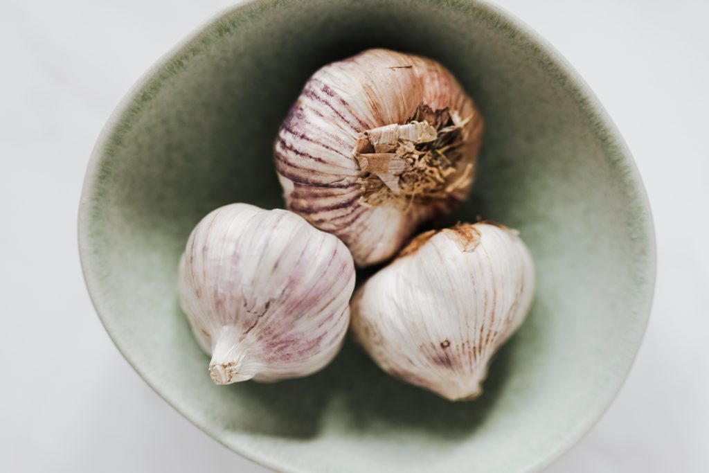 Three heads of whole garlic in a bowl. 