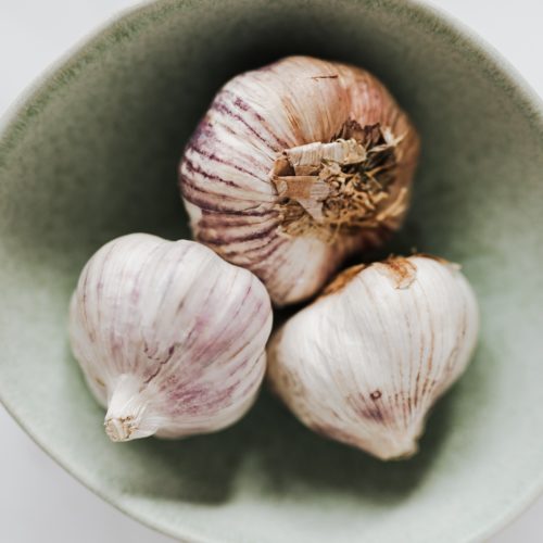 Three heads of whole garlic in a bowl.